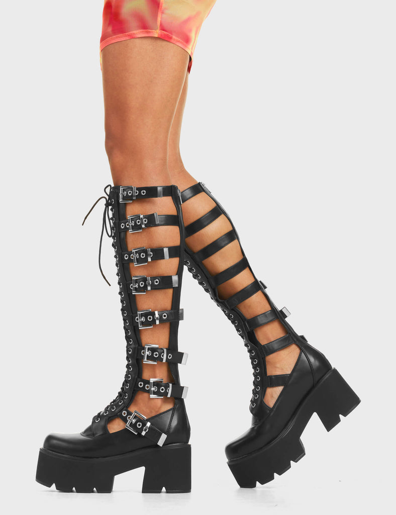 Peakaboo Chunky Platform Knee High Boots in black. Features adjustable straps with silver square buckles running up the leg, and lace-up detailing on the front. 